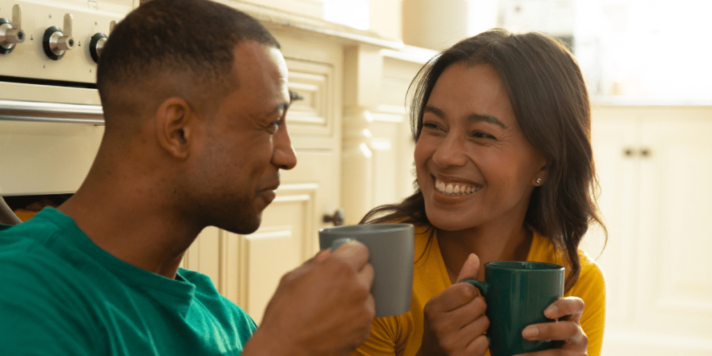 Communication After 40: A couple sharing connection, drinking coffee together, mirroring each other and smiling.